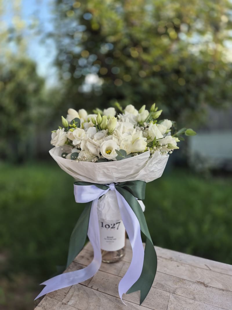 Buchet alb de lisianthus, așezat într-un vas și legat cu panglici albe și verzi