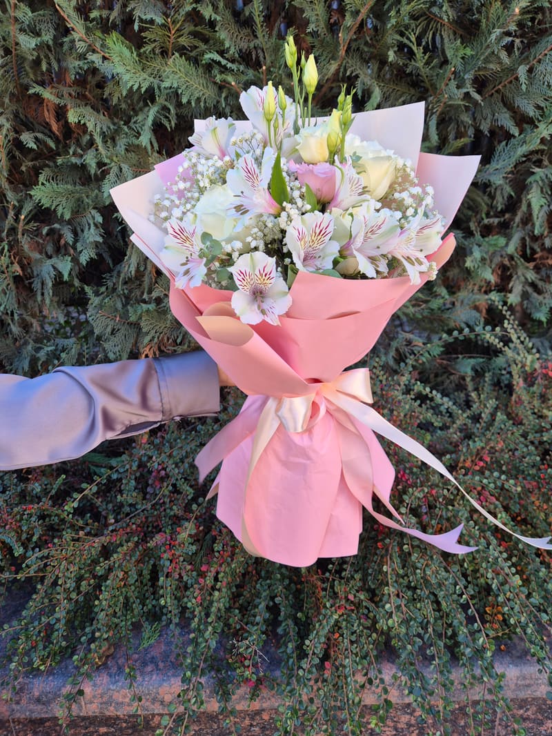 Buchet pastel ambalat în hârtie roz, cu trandafiri, lisianthus și floarea-miresei
