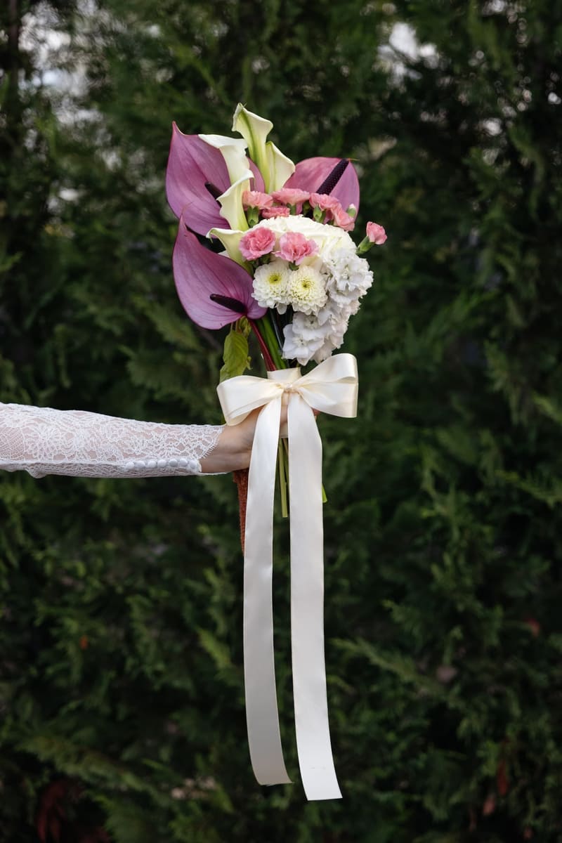 Aranjament floral în roz, mov și alb, legat cu panglici pentru ceremonie